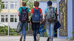 Drei Schüler von hinten auf Schulgelände