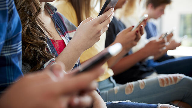 Mehrere Jugendliche mit Smartphones in den Händen.