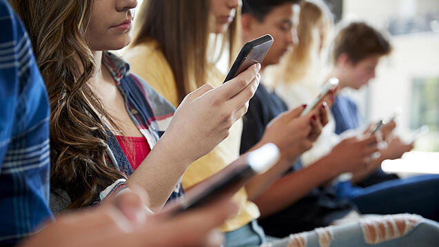 Mehrere Jugendliche mit Smartphones in den Händen.