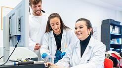 Drei Wissenschaftlerinnen sitzen vor einem Computer und lächeln.