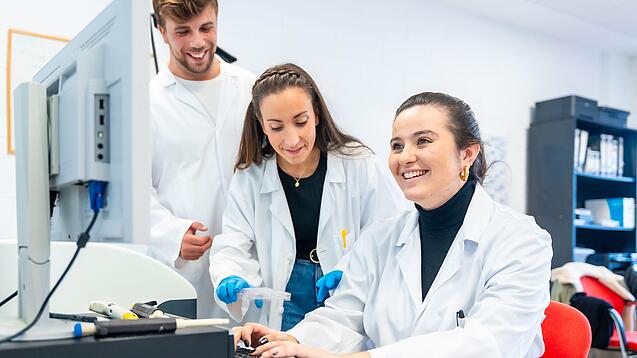 Drei Wissenschaftlerinnen sitzen vor einem Computer und lächeln.