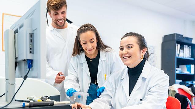 Drei Wissenschaftlerinnen sitzen vor einem Computer und lächeln.