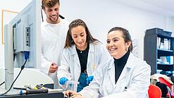 Drei Wissenschaftlerinnen sitzen vor einem Computer und lächeln.