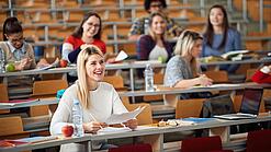 Mehrere Studierende sitzen in einem Hörsaal.