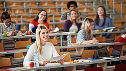 Mehrere Studierende sitzen in einem Hörsaal.