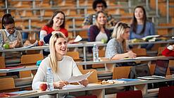 Mehrere Studierende sitzen in einem Hörsaal.