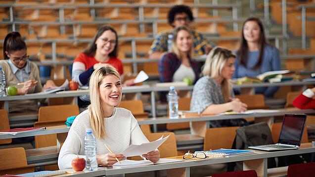 Mehrere Studierende sitzen in einem Hörsaal.