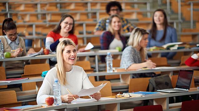 Mehrere Studierende sitzen in einem Hörsaal.