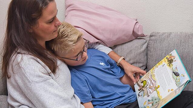 Eine Mutter liest einem Kind aus einem Buch vor. 