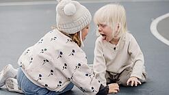 Zwei Kleinkinder schneiden sich gegenseitig Grimassen.