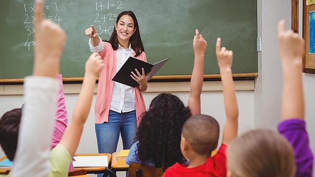 Eine Lehrerin steht in einem Klassenzimmer.