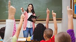 Eine Lehrerin steht in einem Klassenzimmer.