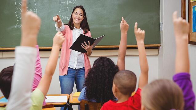 Eine Lehrerin steht in einem Klassenzimmer.