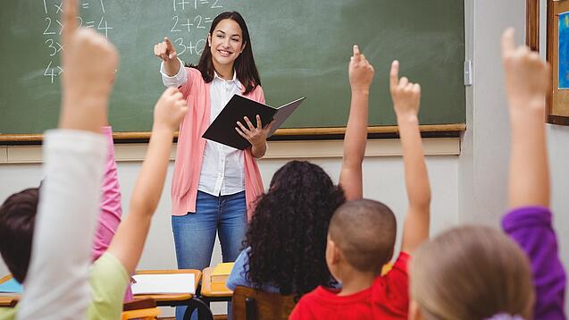 Eine Lehrerin steht in einem Klassenzimmer.