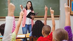 Eine Lehrerin steht in einem Klassenzimmer.
