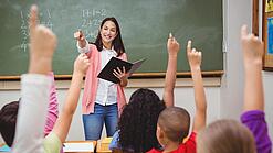 Eine Lehrerin steht in einem Klassenzimmer.
