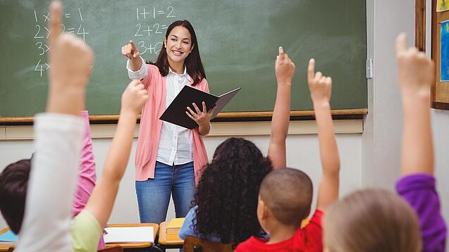 Eine Lehrerin steht in einem Klassenzimmer.