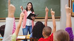 Eine Lehrerin steht in einem Klassenzimmer.