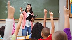 Eine Lehrerin steht in einem Klassenzimmer.