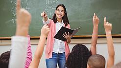 Eine Lehrerin steht in einem Klassenzimmer.