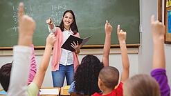Eine Lehrerin steht in einem Klassenzimmer.
