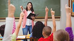 Eine Lehrerin steht in einem Klassenzimmer.