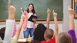 Eine Lehrerin steht in einem Klassenzimmer.