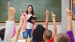 Eine Lehrerin steht in einem Klassenzimmer.