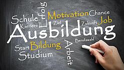Auf einer Tafel sind verschiedene Wörter um das Wort "Ausbildung" gekritzelt, z. B. Arbeit, Studium, Motivation usw.