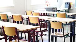 Stühle und Tische in einem Klassenraum.