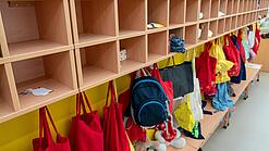An einer Garderobe in einer Kita hängen Rucksäcke von Kindern.
