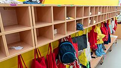 An einer Garderobe in einer Kita hängen Rucksäcke von Kindern.