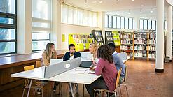 Eine Gruppe Dozierender und Studierender in einer Bibliothek.