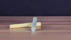 Schulbücher vor einer Tafel in einem Klassenzimmer.