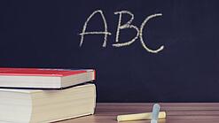 Schulbücher vor einer Tafel in einem Klassenzimmer.