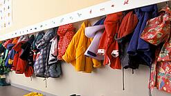 Verschiedene JAcken hängen an einer Garderobe in einer Kita.