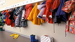 Verschiedene JAcken hängen an einer Garderobe in einer Kita.