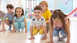 Kleine Kinder hocken auf dem Boden einer Kindertageseinrichtung.