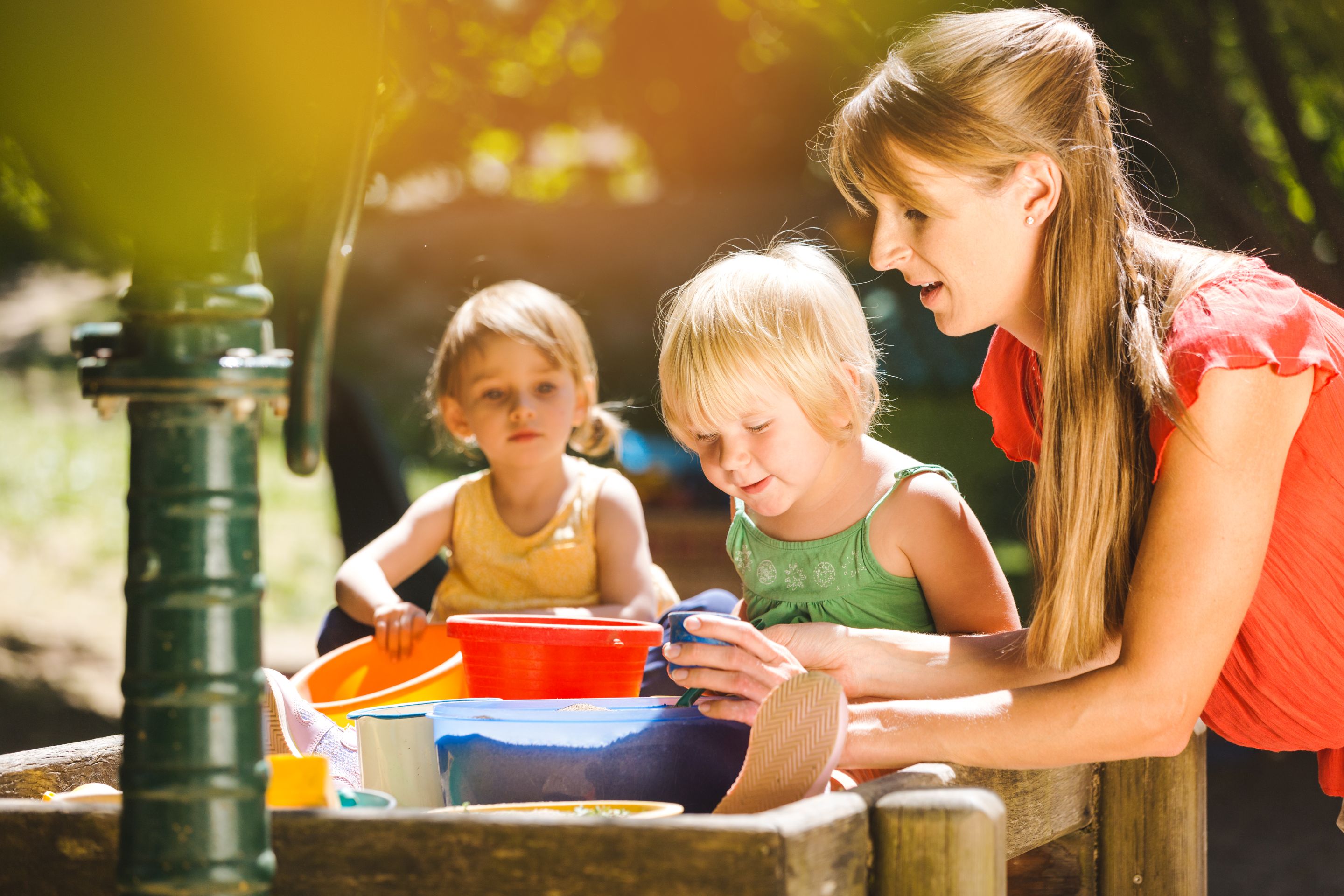Eine pädagogische Fachkraft spielt mit Kindern im Garten.