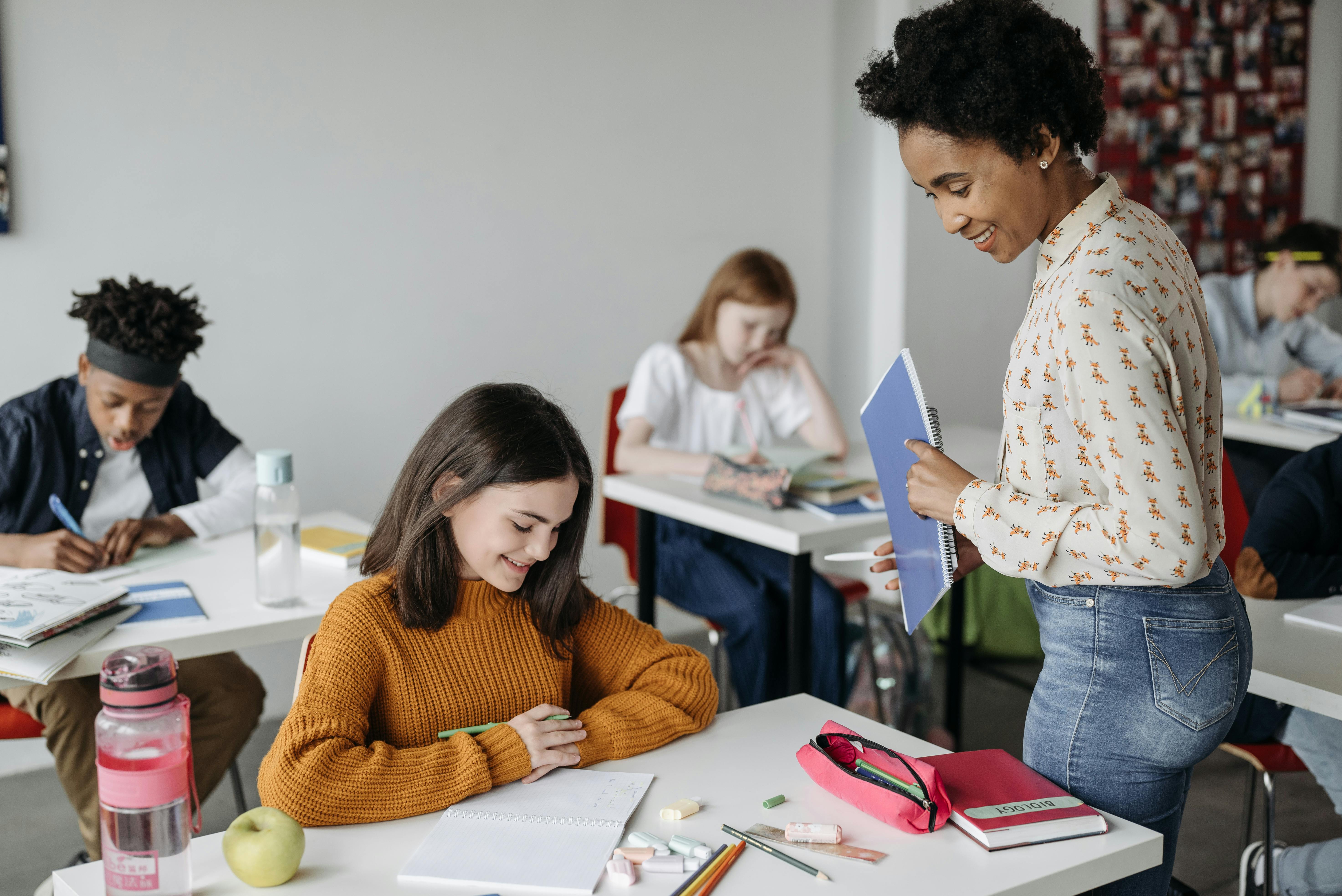Eine Lehrerin schaut einer Schülerin beim Lernen zu.